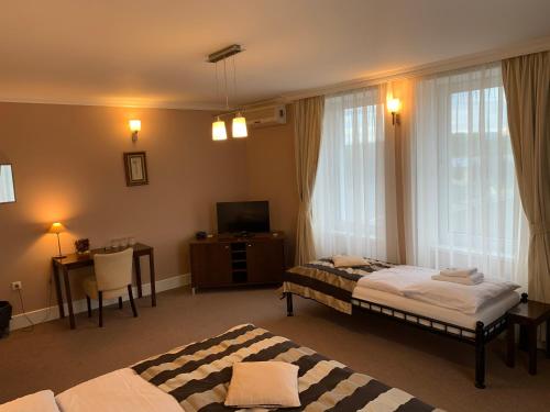 Želiezovce伊甸园宾馆的一间卧室配有两张床、一张桌子和一台电视。