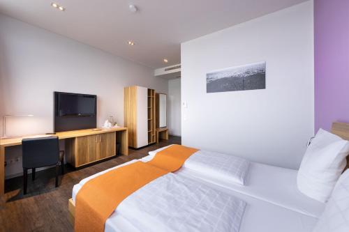 菲尔德施塔特斯图加特梅斯AMH酒店机场店的一间卧室配有一张床、一张书桌和一台电视