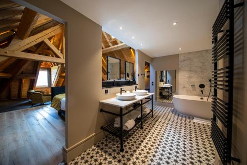 TresservesHôtel L'Incomparable by Les Etincelles的一间带两个盥洗盆和浴缸的浴室以及一间卧室