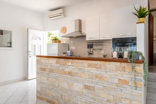 希贝尼克Jadrija Bay的厨房配有白色橱柜和砖墙