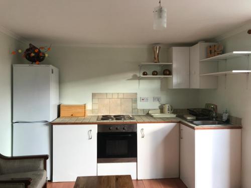 依尔福cosy cottage annex in Fairlop的厨房配有白色橱柜和白色冰箱。