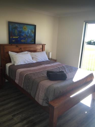 WarnbroLong Beach Retreat Townhouse的一间卧室配有一张大床和木制床头板
