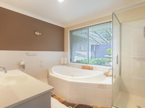 尼尔森湾Serenity Peaceful house with air con Netflix and WI-FI的带浴缸、水槽和窗户的浴室