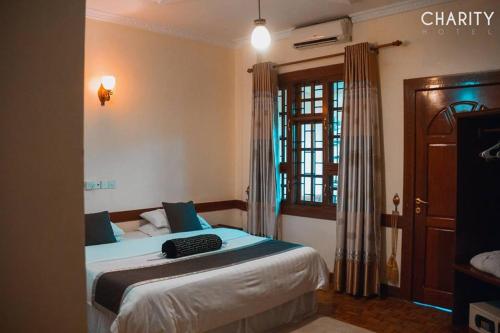 阿鲁沙New Charity Hotel International的一间卧室配有一张带蓝色床单的床和一扇窗户。