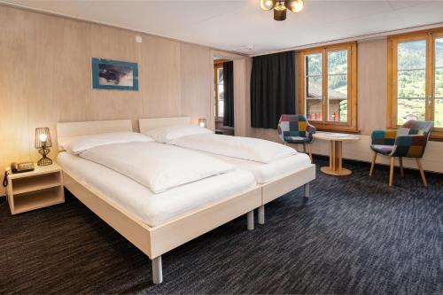 格林德尔瓦尔德瑞士山圣母峰洛奇酒店的卧室配有一张白色大床和椅子