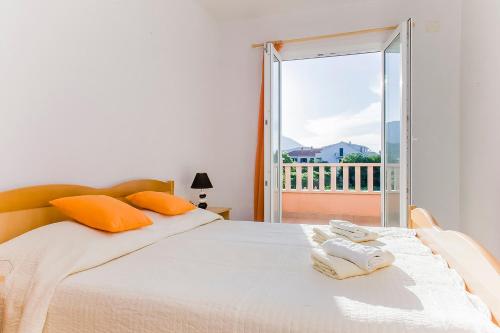 斯瑞瑟尔Apartmani Šundrica的一间卧室配有带橙色枕头的床和窗户。