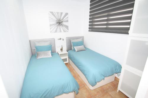英格兰海滩Fantastic apartment near the beach的配有蓝色床单的客房内的两张床