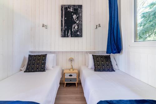 昂贝略昂比热Les minis homes du Bugey - Eco-lodge City, un refuge en hyper centre的配有2张床的白色墙壁和蓝色窗帘