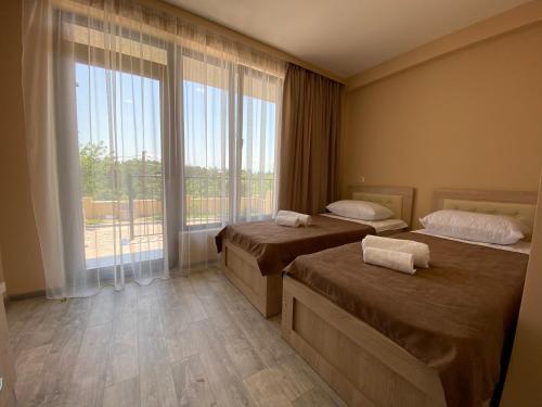 茨卡尔图博Lake House的酒店客房设有两张床和大窗户。