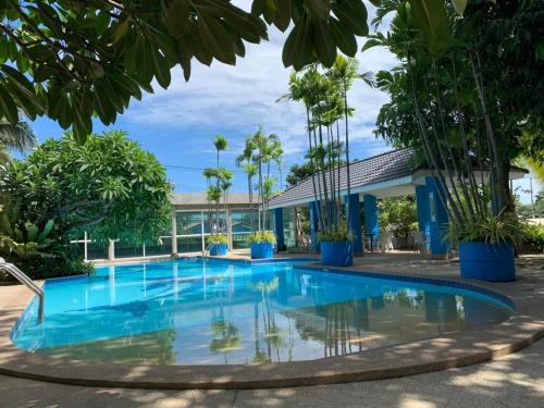 乔木提恩海滩芭堤雅蓝色花园度假宾馆的棕榈树建筑前的游泳池