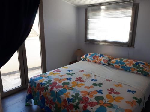 阿格里真托Casa vacanza Mansarda Sanleonina的一间卧室配有一张带花卉床罩的床和两个窗户