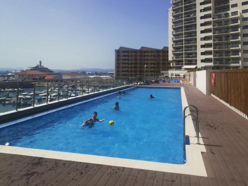 直布罗陀NEW - Kings Wharf Quay29 - Large Studio Apartment with 3 Pools - Gym - Rock Views - Holiday and Short Let Apartments in Gibraltar的一群人在一座大楼的游泳池里