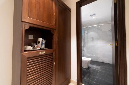 马斯喀特阿尔哈塔里酒店的带淋浴的浴室和木制橱柜。