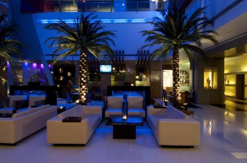 纳威孟买滕伽里根扎酒店的大堂在晚上设有白色的沙发和棕榈树