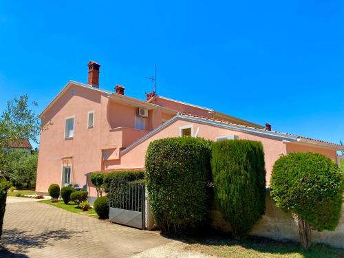 法扎纳Apartments Prodan的前面有灌木丛的粉红色房子