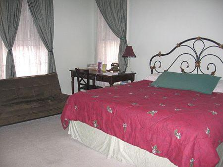特洛伊奥尔德法官大厦住宿加早餐酒店的一间卧室配有红色的床、一张书桌和窗户。