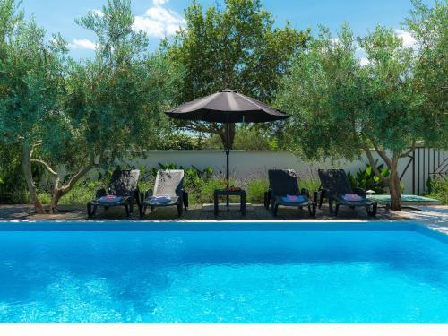 罗波里卡Holiday Home Neja by Interhome的一组椅子和一把遮阳伞,位于游泳池旁