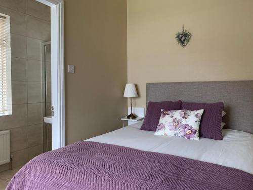 波塔姆纳Oak Lodge Portumna的一张带紫色毯子和枕头的床