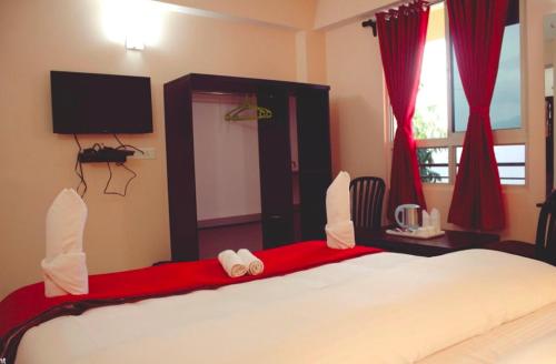 甘托克Bankhim Residency (Parking available)的一间卧室配有一张带红色窗帘的大床