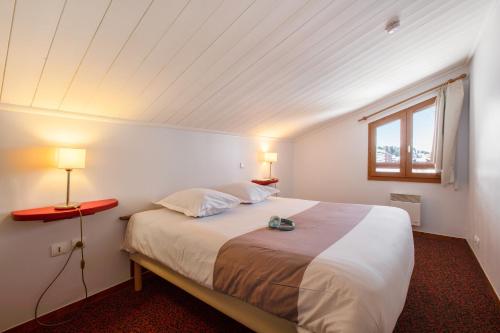 拉普拉涅Résidence Pierre & Vacances Le Mont Soleil的一间卧室配有一张带两盏灯的床和一扇窗户。