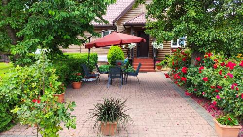 MońkiAgroturystyka u Pruszyńskich的庭院设有椅子和遮阳伞,鲜花盛开