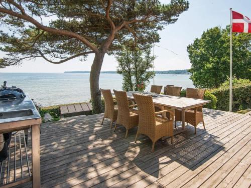 桑德比耶特6 person holiday home in Bjert的一个带桌椅的木制甲板和大海
