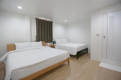 曼谷INTERest POSHTEL的酒店客房设有两张床和窗户。