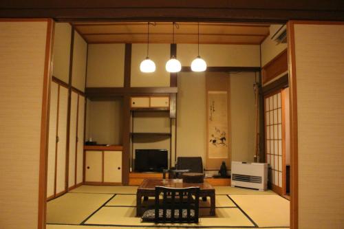 ŌwaniHistorical Ryokan SENYUKAN的客厅配有桌椅和灯