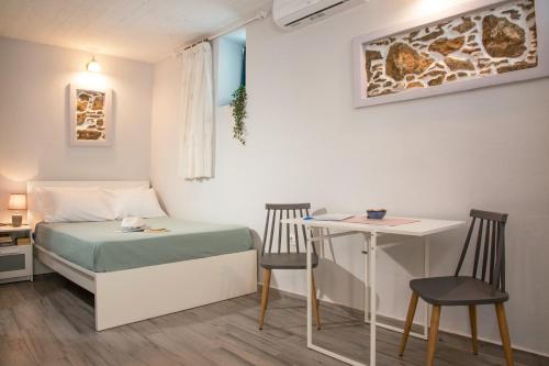 斯基罗斯岛Studio Cozy - In the Heart of Skyros Village的小房间设有一张床、一张桌子和椅子