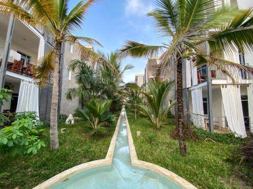 迪亚尼海滩Aqua Resort的棕榈树建筑前的游泳池