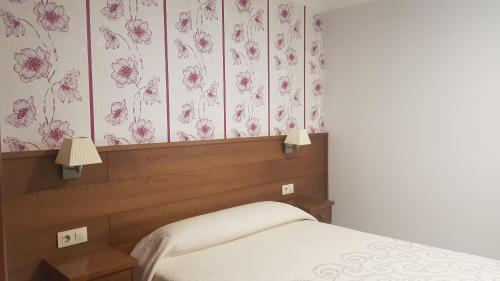 波伊奥卡萨富恩特斯酒店的一间卧室配有一张粉红色花卉壁纸的床