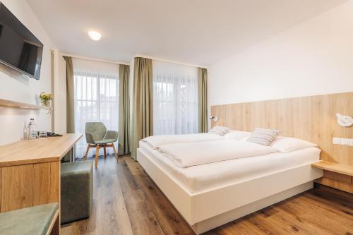 奥托博伊伦巴尔赫伽尼酒店的卧室配有一张白色大床和一张书桌