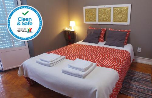 里斯本Alvalade II Airport Guest House的卧室配有红色和白色的床,提供毛巾