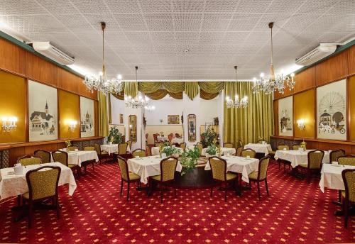 维也纳奥地利-维也纳酒店的用餐室配有白色桌椅和吊灯。