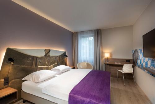 罗森海姆罗森海姆温德姆特里普酒店的酒店客房设有一张大床和一张书桌。