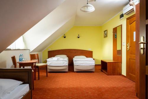 奥得河畔科斯琴巴斯提翁酒店的一间卧室配有两张床和一张桌子及椅子