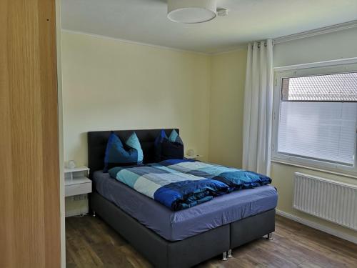 格奥尔格斯马林许特Ferienwohnung - Nadine的一间卧室配有一张带蓝色枕头的床和一扇窗户。