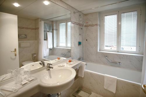 卢加诺西加藤丽都酒店的浴室配有盥洗盆、浴缸、卫生间和镜子