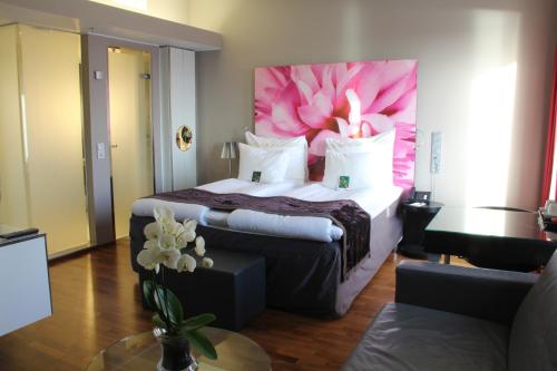 卑尔根卑尔根机场凯瑞酒店的酒店客房设有一张大床,墙上挂着粉红色的花朵