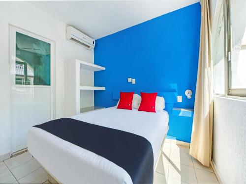 阿卡普尔科Capital O Hotel El Mejicano, Acapulco的蓝色和白色的卧室,配有红色枕头的床