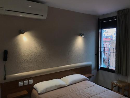 巴塞罗那Hostal Radio Barcelona的一间卧室配有床、窗户和灯