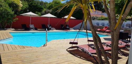 诺亚芒提亚La Villa en L'île - 2 Piscines & Spa的木制甲板上配有椅子和遮阳伞的游泳池