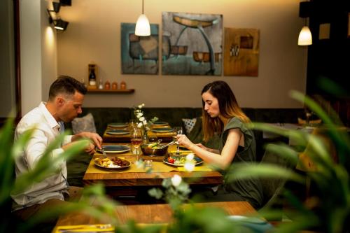瑙吉考尼饶Hotel Vineyard Inn - Szőlőskert的坐在餐桌旁吃食物的男人和女人