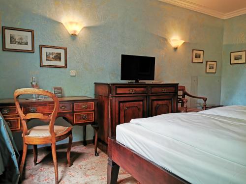 慕尼黑Hotel Altmünchen by Blattl的一间卧室配有一张床和一张书桌及电视
