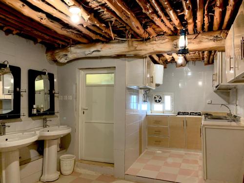 塔诺马بيت القرية التراثية的一间带两个盥洗盆和木制天花板的浴室