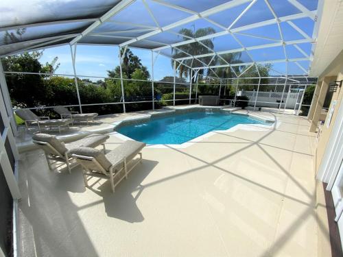 奥兰多Mickeys Pearl - Phenomenal 7BR with 4 Master Suites Privacy Pool & Hot Tub Gas BBQ - 2 miles to Disney的一个带游泳池、椅子和遮阳伞的庭院