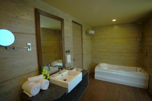 甘德希罕Renest Gandhidham的一间带水槽、浴缸和镜子的浴室