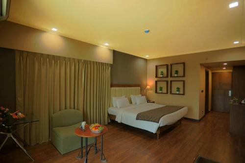 甘德希罕Renest Gandhidham的大型酒店客房设有一张床铺和一张桌子。