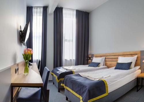 华沙Hotel Mokotów的酒店客房设有两张床和一张桌子。