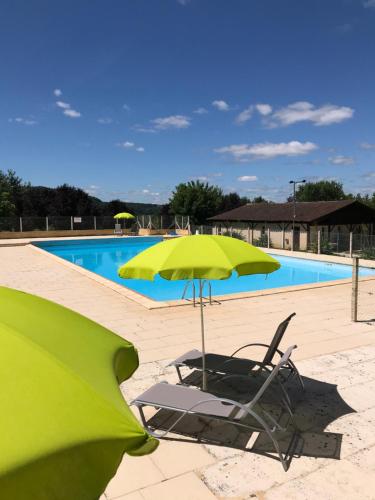 Saint-Julien-de-LamponCamping Le Mondou的游泳池旁的一把绿色遮阳伞和一把椅子